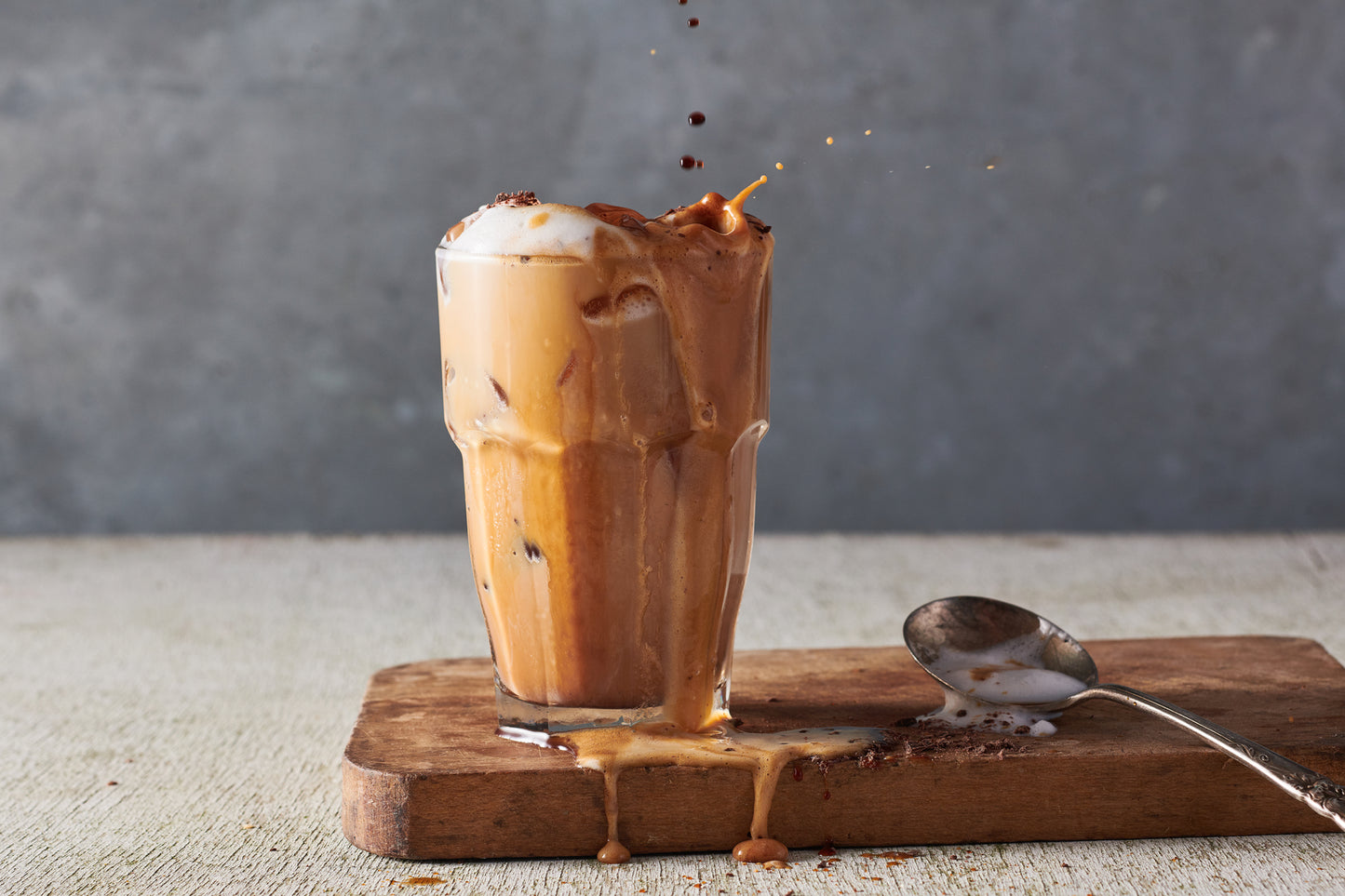 Kohana coffee cold brew mocha frappe in a glass on a table with a spoon next to it